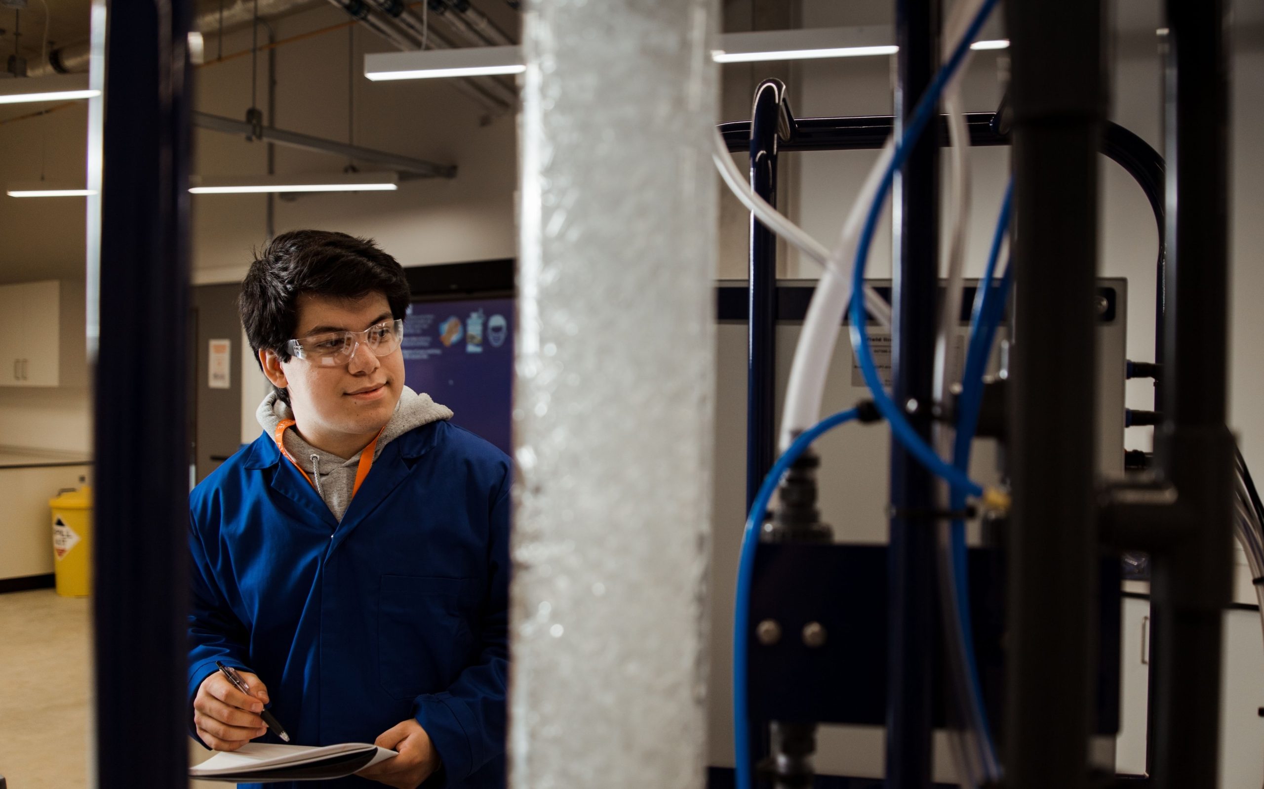 Student in navy blue lab coat and protective eyewear.